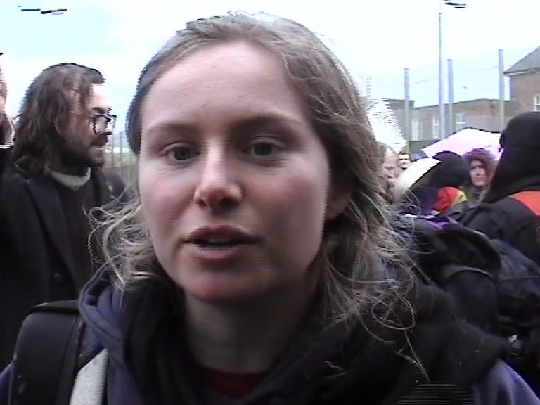 A woman with fair hair amongst protesters outside a prison.